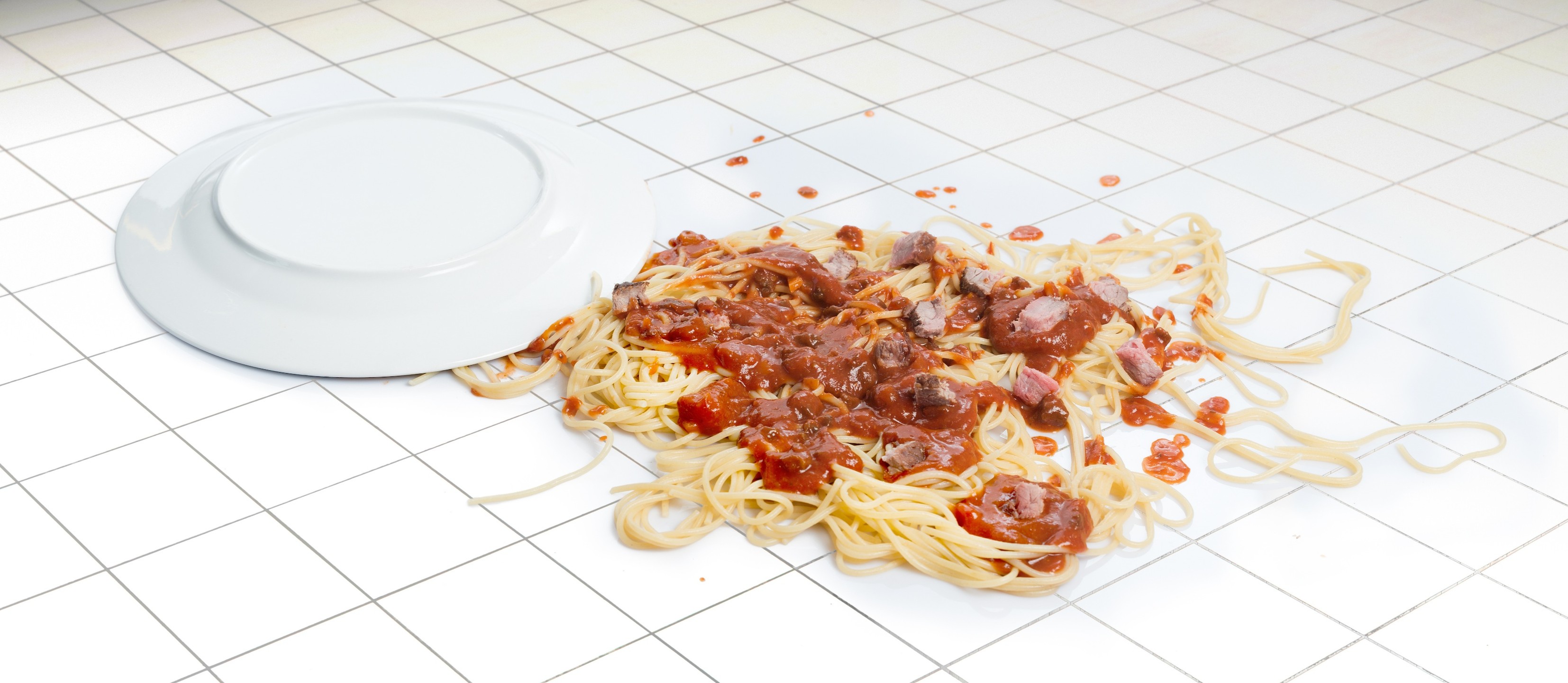 spaghetti splattered on a white tile floor